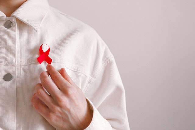 person in white shirt with a red ribbon pinned to it